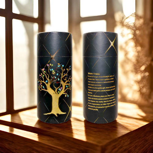Two black cylindrical containers with tree designs on a wooden surface.